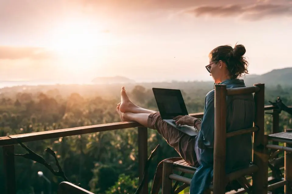 a female digital nomad using her laptop in a rural place